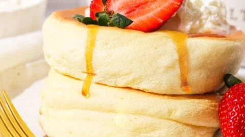 Fluffy Japanese soufflé pancakes stack topped with syrup and fruits
