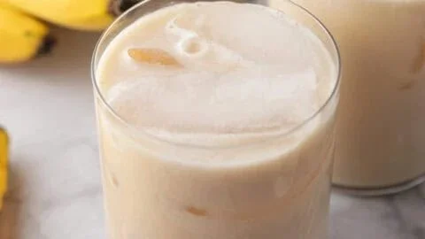A glass of Korean Banana Milk served with fresh bananas.